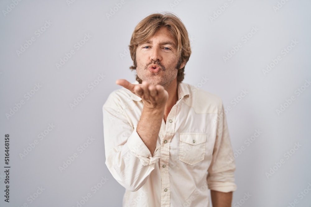 Middle age man standing over isolated background looking at the camera blowing a kiss with hand on air being lovely and sexy. love expression. Middle age man standing over isolated background looking at the camera blowing a kiss with hand on air being lovely and sexy. love expression.