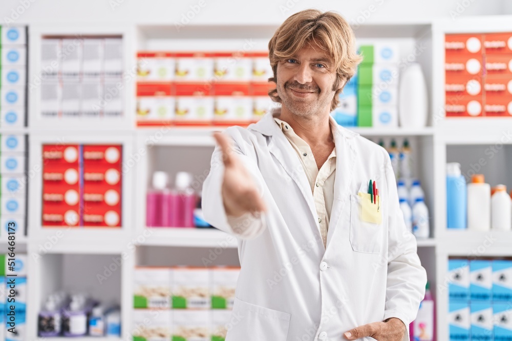 Young man pharmacist smiling confident shake hand at pharmacy