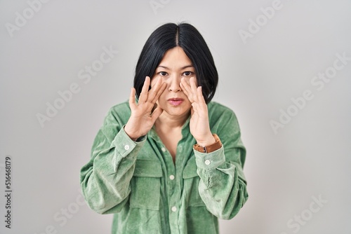 Young asian woman standing over white background hand on mouth telling secret rumor, whispering malicious talk conversation