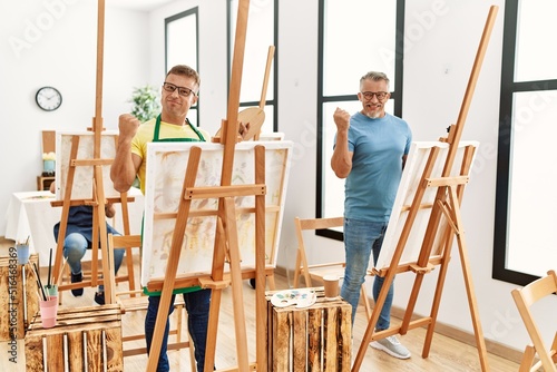 Group of middle age people artist at art studio screaming proud, celebrating victory and success very excited with raised arms