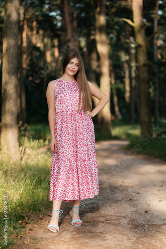 Lovely girl in pink summer dress on forest road