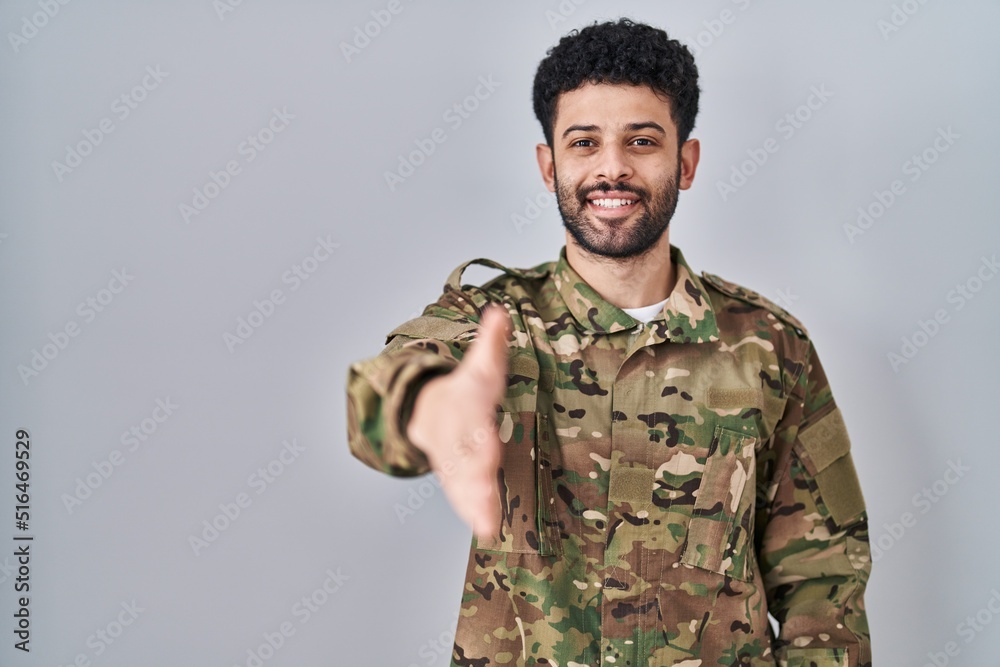 Arab man wearing camouflage army uniform smiling friendly offering handshake as greeting and welcoming. successful business.