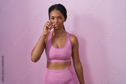 African american woman with braids wearing sportswear over pink background mouth and lips shut as zip with fingers. secret and silent, taboo talking