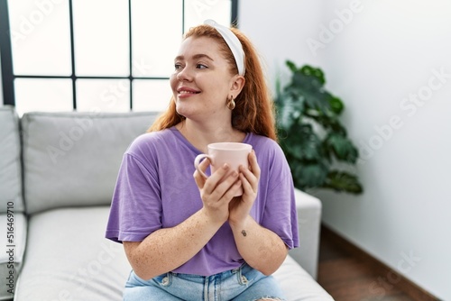 Young redhead woman smiling confident drinking coffee at home