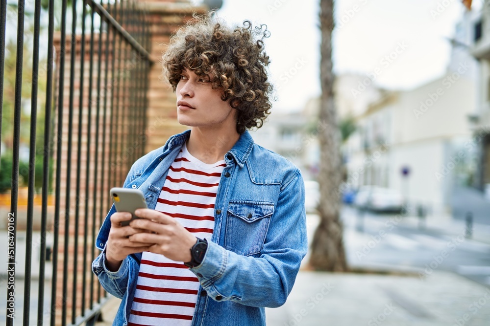 Fototapeta premium Young hispanic man using smartphone at the city