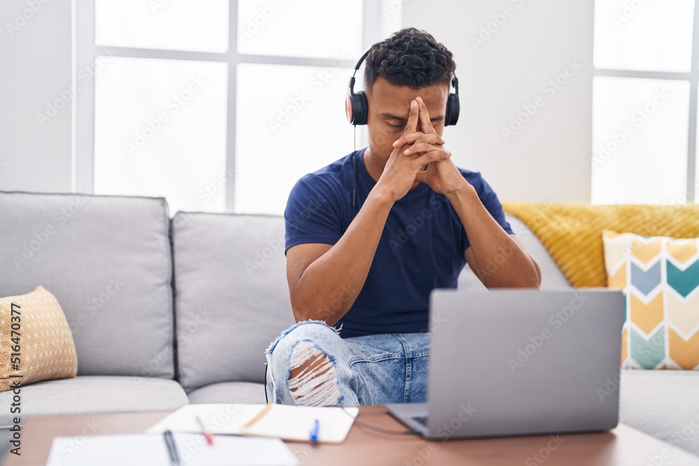 Young latin man sitting on sofa studying stressed at home Young latin man sitting on sofa studying stressed at home
