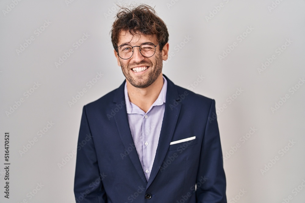 Hispanic business man wearing glasses winking looking at the camera with sexy expression, cheerful and happy face. Hispanic business man wearing glasses winking looking at the camera with sexy expression, cheerful and happy face.