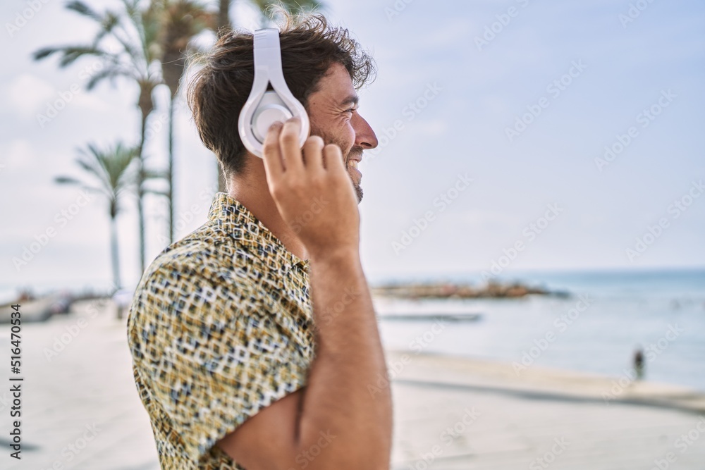 Young hispanic man smiling confident listening to music at seaside