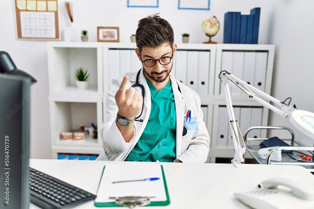 Young man with beard wearing doctor uniform and stethoscope at the clinic beckoning come here gesture with hand inviting welcoming happy and smiling Young man with beard wearing doctor uniform and stethoscope at the clinic beckoning come here gesture with hand inviting welcoming happy and smiling