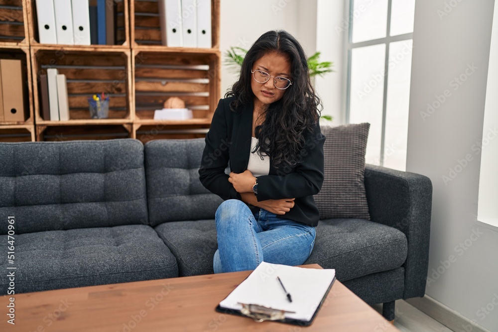 Young asian woman at consultation office with hand on stomach because indigestion, painful illness feeling unwell. ache concept. Young asian woman at consultation office with hand on stomach because indigestion, painful illness feeling unwell. ache concept.