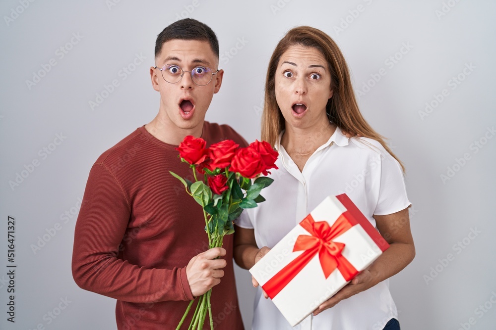 Mother and son holding mothers day gift afraid and shocked with surprise and amazed expression, fear and excited face. Mother and son holding mothers day gift afraid and shocked with surprise and amazed expression, fear and excited face.