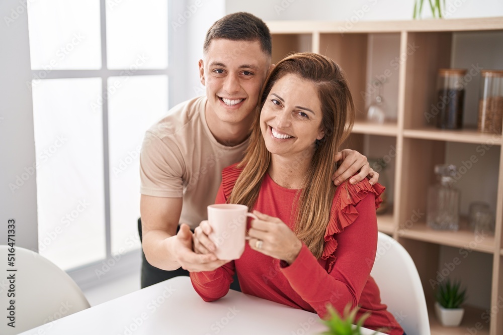 Man and woman mother and son drinking coffee sitting on table at home Man and woman mother and son drinking coffee sitting on table at home
