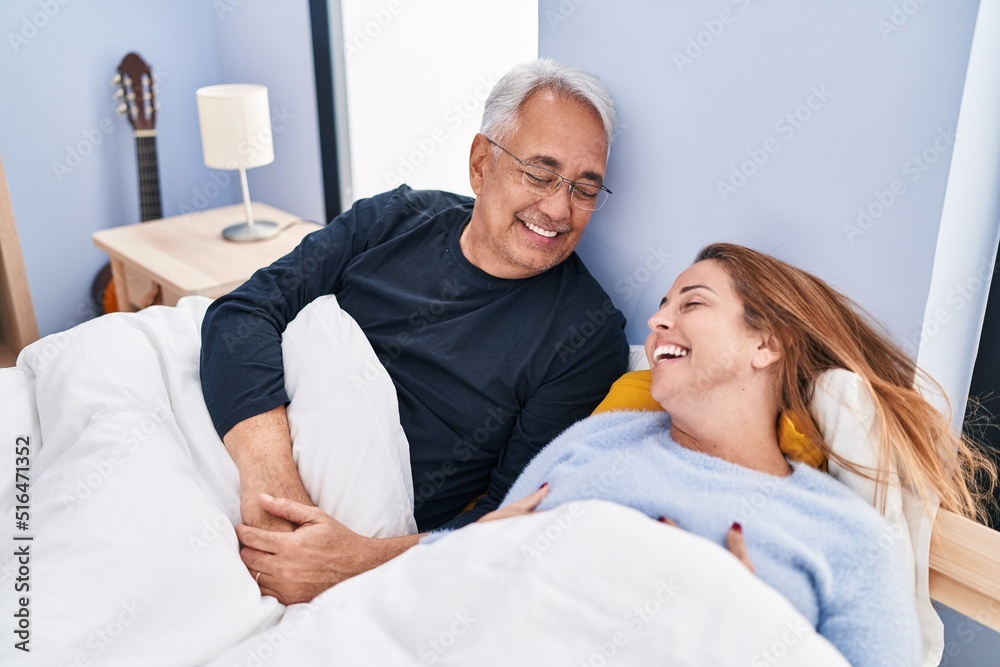 Middle age man and woman couple smiling confident lying on bed at bedroom Middle age man and woman couple smiling confident lying on bed at bedroom