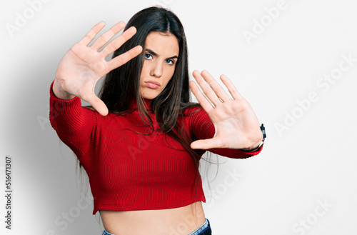 Young brunette teenager wearing red turtleneck sweater doing frame using hands palms and fingers, camera perspective © Krakenimages.com