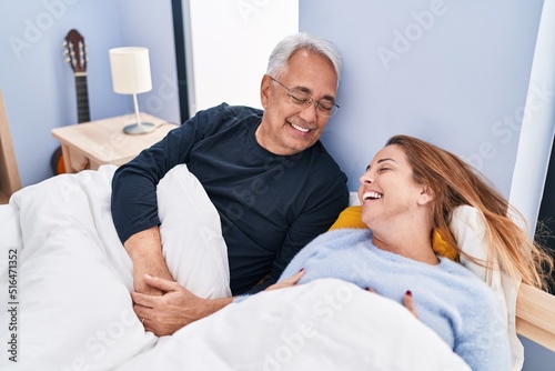 Middle age man and woman couple smiling confident lying on bed at bedroom
