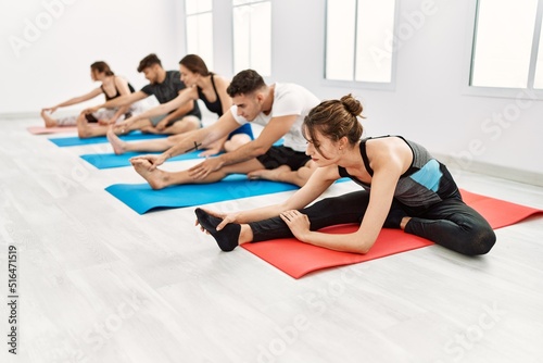 Group of young hispanic people concentrate training yoga at sport center.