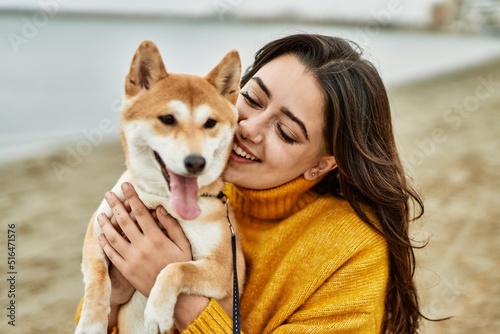 Beautiful young woman hugging happy shiba inu dog at the beach © Krakenimages.com