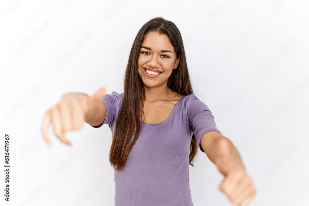 Young brunette woman standing by isolated background approving doing positive gesture with hand, thumbs up smiling and happy for success. winner gesture. Young brunette woman standing by isolated background approving doing positive gesture with hand, thumbs up smiling and happy for success. winner gesture.