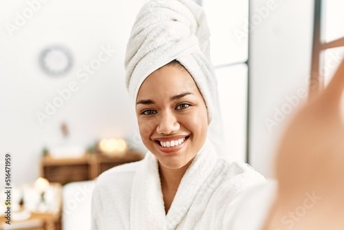 Young latin woman wearing bathrobe make selfie by the camera at beauty center