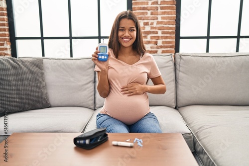 Young pregnant woman checking blood sugar smiling with a happy and cool smile on face. showing teeth. photo