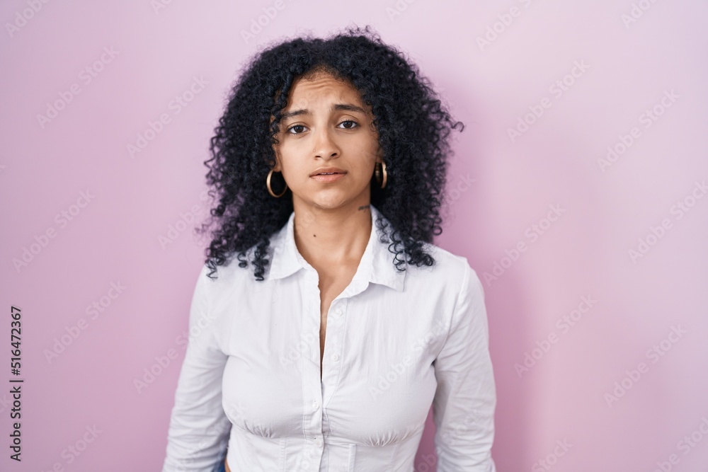 Hispanic woman with curly hair standing over pink background looking sleepy and tired, exhausted for fatigue and hangover, lazy eyes in the morning. Hispanic woman with curly hair standing over pink background looking sleepy and tired, exhausted for fatigue and hangover, lazy eyes in the morning.