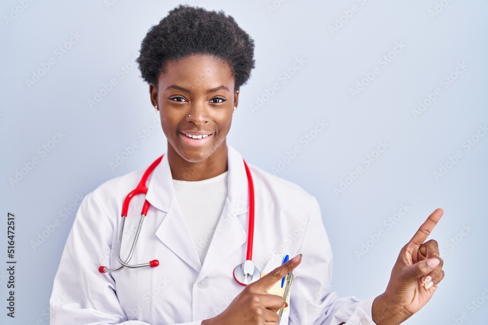African american woman wearing doctor uniform and stethoscope smiling and looking at the camera pointing with two hands and fingers to the side. African american woman wearing doctor uniform and stethoscope smiling and looking at the camera pointing with two hands and fingers to the side.
