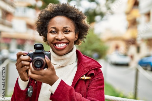 Young african american woman holding dslr camera at the city © Krakenimages.com