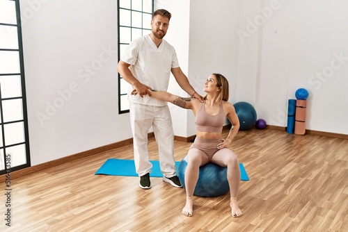 Physioterapist man giving rehab treatment to woman at the clinic.