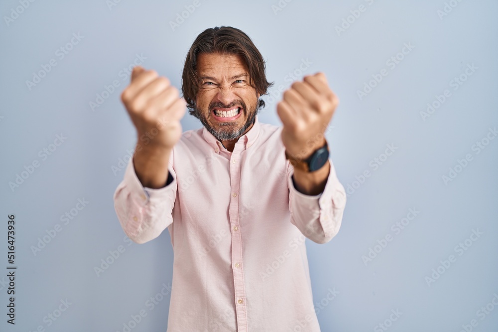 Handsome middle age man wearing elegant shirt background angry and mad raising fists frustrated and furious while shouting with anger. rage and aggressive concept. Handsome middle age man wearing elegant shirt background angry and mad raising fists frustrated and furious while shouting with anger. rage and aggressive concept.
