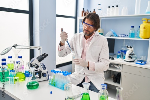Handsome middle age man working at scientist laboratory smiling happy pointing with hand and finger