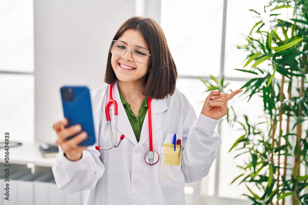 Young hispanic doctor woman working on online appointment smiling happy pointing with hand and finger to the side Young hispanic doctor woman working on online appointment smiling happy pointing with hand and finger to the side