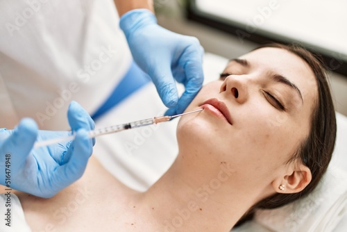 Doctor man injecting botox on woman lips for anti aging treatment at the clinic.