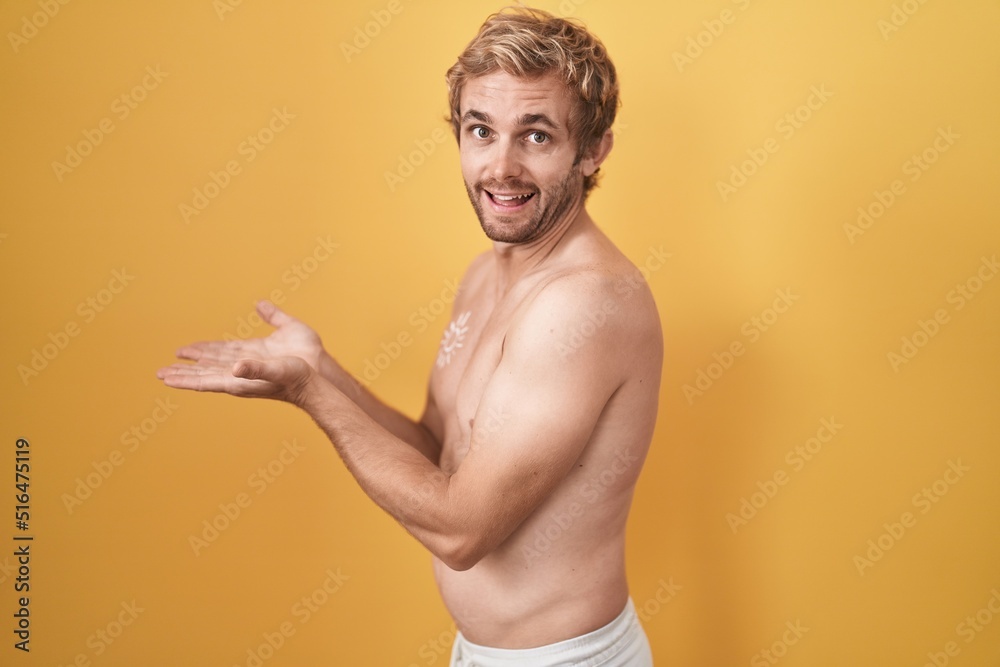 Caucasian man standing shirtless wearing sun screen pointing aside with hands open palms showing copy space, presenting advertisement smiling excited happy
