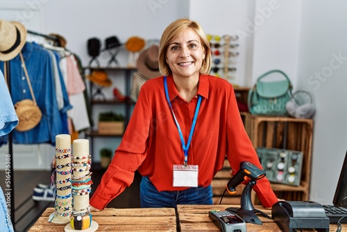 Middle age blonde woman smiling confident working at clothing store