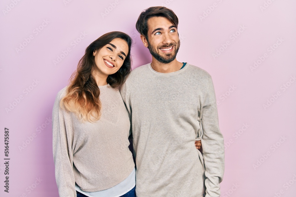 Young hispanic couple wearing casual clothes smiling looking to the side and staring away thinking.