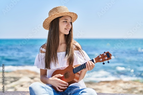 Adorable girl tourist smiling confident playing ukulele at seaside photo