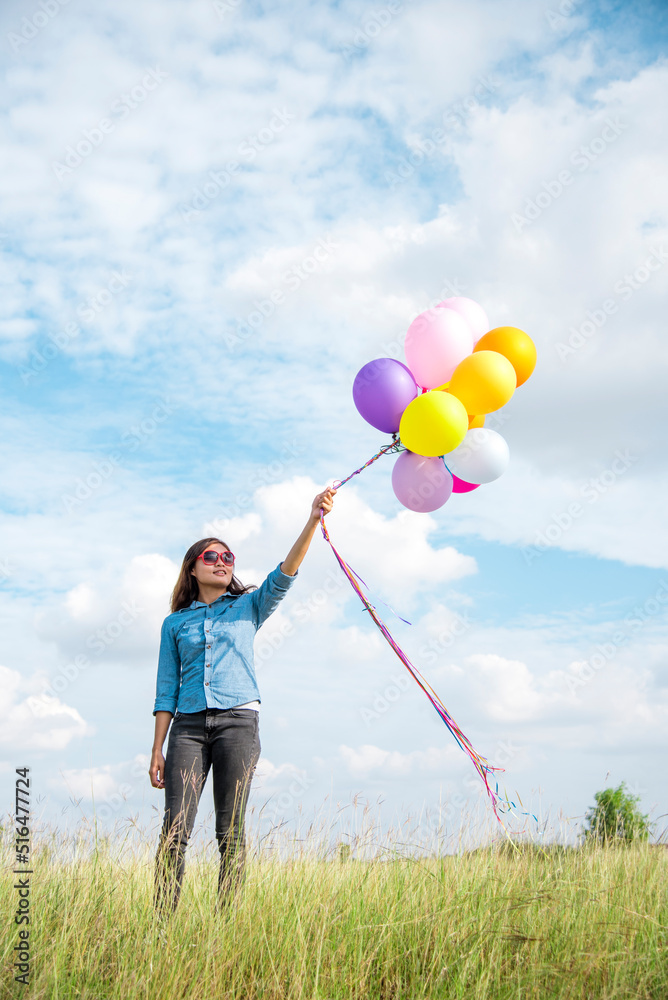 Woman holding balloons running on green meadow white cloud and blue sky with happiness Cheerful and relax. Hands holding vibrant air balloons play on birthday party happy times summer sunlight outdoor Woman holding balloons running on green meadow white cloud and blue sky with happiness Cheerful and relax. Hands holding vibrant air balloons play on birthday party happy times summer sunlight outdoor