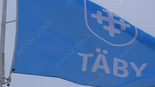 Footage shot in 4K, displaying the logo of Täby municipality (kommun) on a blue flag. Swedish governance and local politics concept. photo