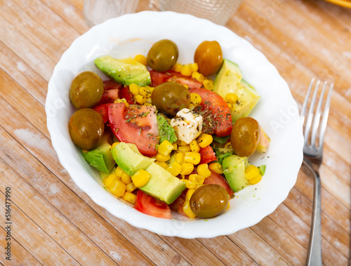 Fresh salad with olives, tomatoes, corn and cheese on a plate