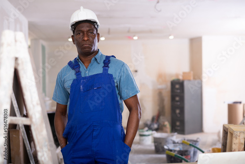 Portrait of an african american builder standing on a construction site indoors during repair work