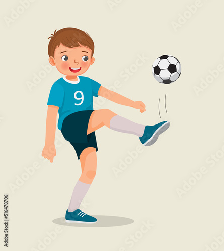 cute little boy playing soccer practicing kicking the football 