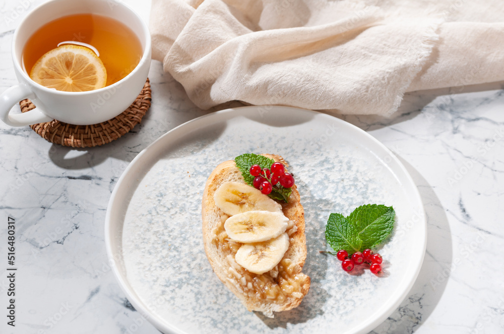 Appetizer sandwich with banana, red currant and mint greens. Tea with lemon. Appetizer sandwich with banana, red currant and mint greens. Tea with lemon.