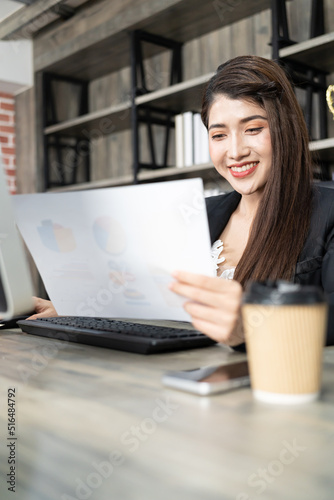 Portrait of pretty business woman using computer at workplace in an office. positive business lady smiling looking on paper.