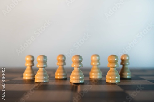 White pawns on a chessboard with the white background. Victory of white pawns. Symmetrical composition with chess pieces. Board game strategy.