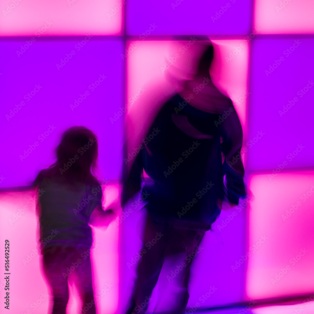 Children dance at the disco on glowing panels, blurry background. Blurry movement of people dancing