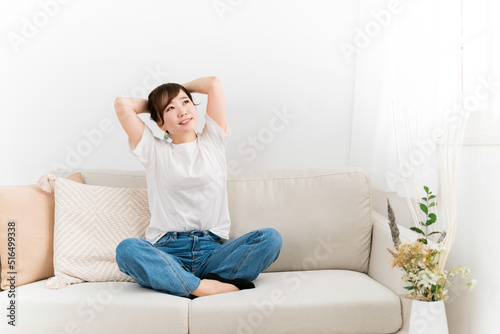 家のソファでくつろぐジーンズ姿の日本人女性（笑顔） 