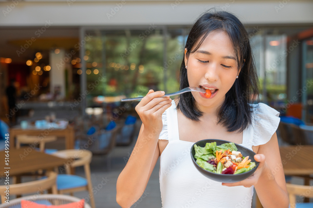 Woman eating Breakfast and play smart phone. Fruits such as watermelon, papaya, melon, passion fruit, orange juice and coffee. placed on a gray placemat Woman eating Breakfast and play smart phone. Fruits such as watermelon, papaya, melon, passion fruit, orange juice and coffee. placed on a gray placemat