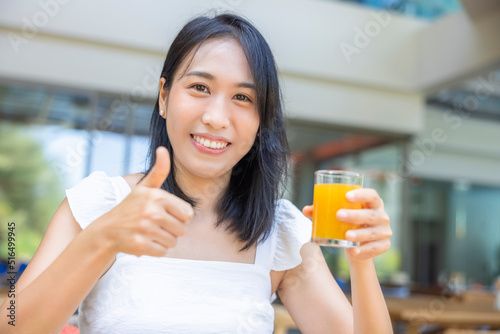 Woman thumbs up and holding a glass of orange juice for eating Breakfast