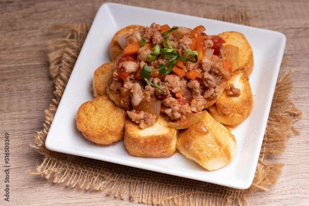 Fried tofu stir fried with ground pork and vegetables in white plate