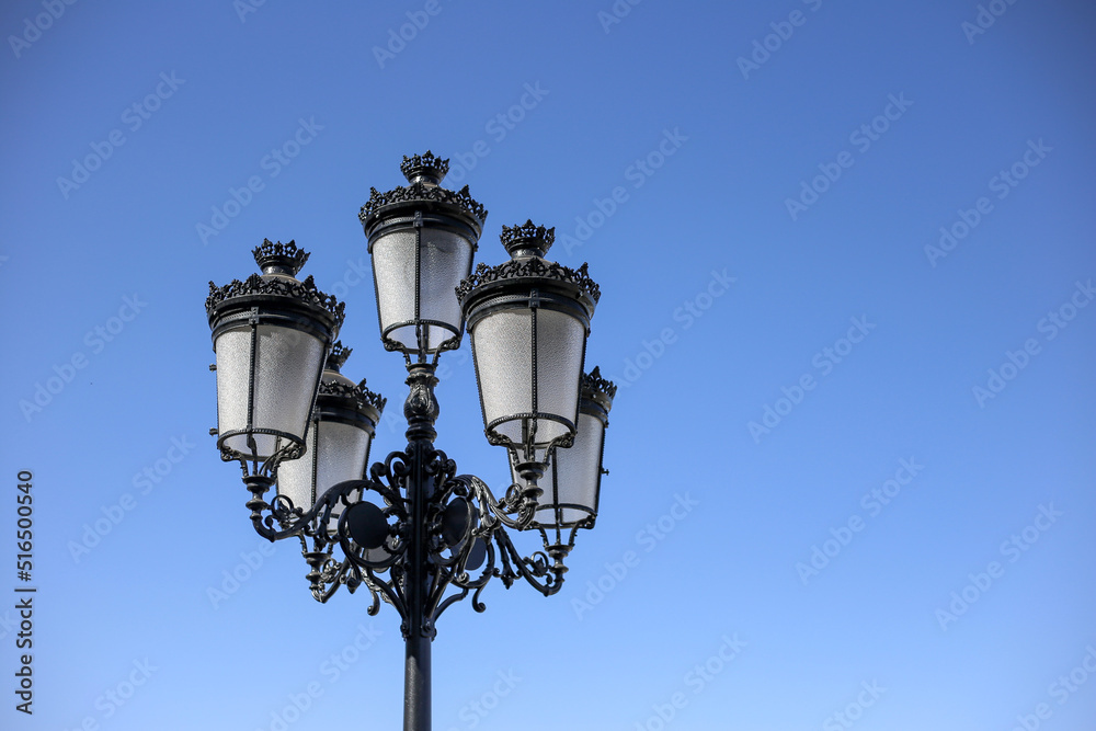 Black vintage street lamp on the blue sky background